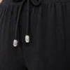 280720266a67fa1ab2bce.webp Battal Beden Bürümcük Kumaş Beli Lastikli Bağcıklı Bol Paça Palazzo Pantolon - Siyah